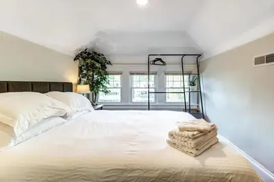 a white bedroom with a large bed and a window at Cozy studio near Cleve Clinic Case in Cleveland Heights