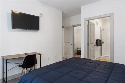 a bedroom with a bed and a desk and a flat screen tv at Cozy 6BR 6BA combined Apartments Near Downtown Cincinnati in Cincinnati