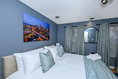 a bedroom with a white bed with a painting on the wall at Lux Ohio City Gem in Cleveland