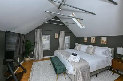 a bedroom with a large white bed and a green chair at Lux Ohio City Gem in Cleveland