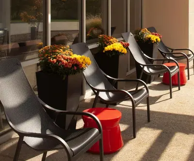 a row of chairs in front of a building with flowers at Home2 Suites by Hilton Canton in North Canton