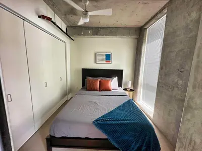 a bedroom with a bed with a blue blanket on it at 4 Brand new combined apartments with city views in Cleveland