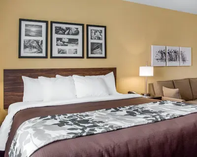 a bedroom with a large bed and a chair at Sleep Inn & Suites Parkersburg - Mineral Wells in Parkersburg