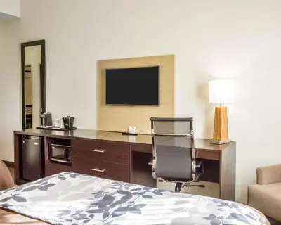 a bedroom with a desk with a television and a chair at Sleep Inn & Suites Parkersburg - Mineral Wells in Parkersburg