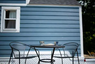 a table and two chairs in front of a blue house at Tiny House Strouds Run Lake in Athens