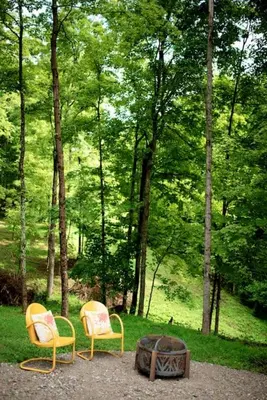 two chairs sitting next to a fire in a forest at Tiny House Strouds Run Lake in Athens