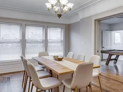 a dining room with a wooden table and white chairs at Upscale Historic Home near Downtown, Hall of Fame, Beach, Arenas in Cleveland