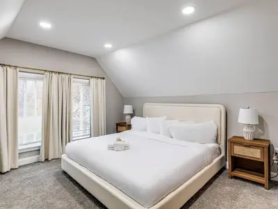 a bedroom with a large white bed and two windows at Upscale Home near Downtown Cle, R&R HoF, Beach, Arena in Cleveland