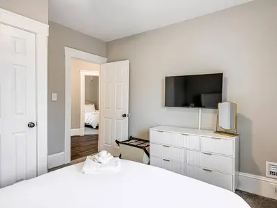 a bedroom with a white bed and a tv at Upscale Home near Downtown Cle, R&R HoF, Beach, Arena in Cleveland