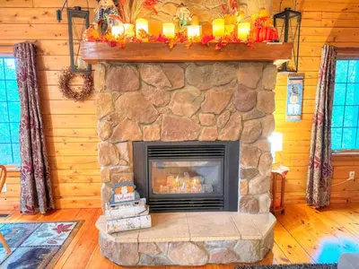 a living room with a stone fireplace in a cabin at Ferngully Creek Cabins in Millersburg