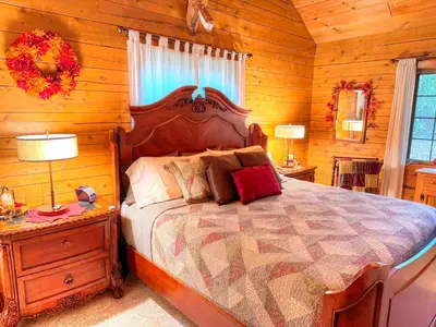 a bedroom with a large bed in a log cabin at Ferngully Creek Cabins in Millersburg