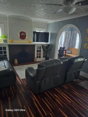 a living room with a black leather couch and a fireplace at Leisure guest home in Lorain