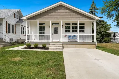 a white house with a porch and a lawn at Lake Erie Serenity Hutch in Port Clinton