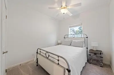 a white bedroom with a bed and a ceiling fan at Lake Erie Serenity Hutch in Port Clinton