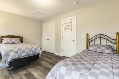 two beds in a bedroom with white walls and wood floors at 24 Mi to Cincinnati Newly Built Bethel Home! in Batavia