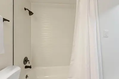 a bathroom with a white shower curtain and a toilet at The Reynoldsburg Getaway in Reynoldsburg