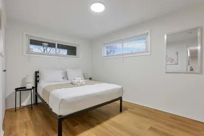 a bedroom with a bed with white walls and windows at The Reynoldsburg Getaway in Reynoldsburg