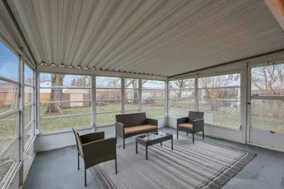 a screened in porch with chairs and tables and windows at The Reynoldsburg Getaway in Reynoldsburg