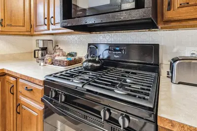 a kitchen with a stove with a tea kettle on it at The Henry House I Pet Friendly Cozy Convenient in Fairview Park