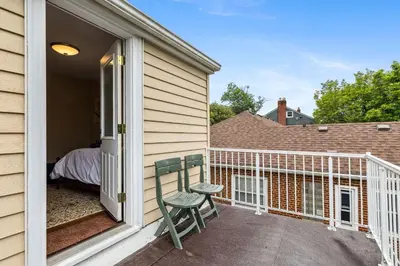 a porch with a chair and a bed on a balcony at The Henry House I Pet Friendly Cozy Convenient in Fairview Park
