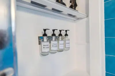 four bottles of wine sitting on a shelf in a bathroom at The Henry House I Pet Friendly Cozy Convenient in Fairview Park