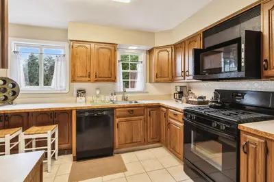 a kitchen with wooden cabinets and black appliances at The Henry House I Pet Friendly Cozy Convenient in Fairview Park
