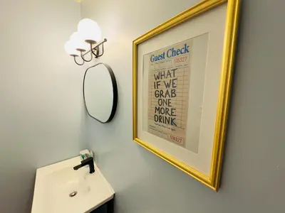 a bathroom with a mirror and a picture on the wall at The Cocktail Cabin! 2 Miles to Cedar Point in Sandusky