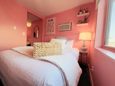 a bedroom with pink walls and a white bed at Cocktail Cabin Themed Guest Room in Sandusky