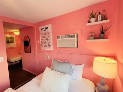 a bedroom with pink walls and a bed with a lamp at Cocktail Cabin Themed Guest Room in Sandusky