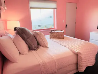 a bedroom with a bed with pink walls and a window at Cocktail Cabin Themed Guest Room in Sandusky