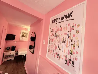 a pink room with a poster of wine bottles at Cocktail Cabin Themed Guest Room in Sandusky