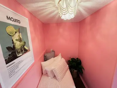 a pink room with a bed and a chandelier at Cocktail Cabin Themed Guest Room in Sandusky