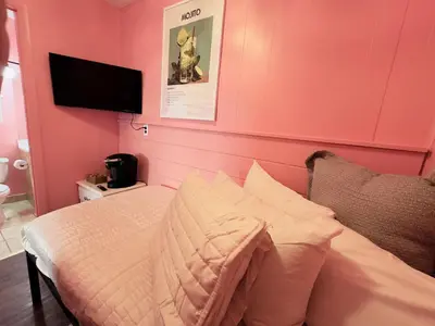 a bedroom with a bed with a pink wall at Cocktail Cabin Themed Guest Room in Sandusky