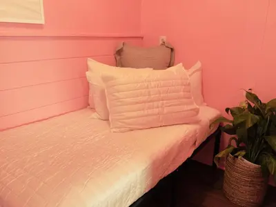a pink room with a bed with white pillows at Cocktail Cabin Themed Guest Room in Sandusky