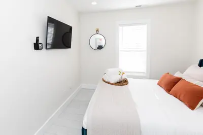 a white bedroom with a bed and a tv at Family Duplex Suite in Downtown Sandusky Sleeps 12! in Sandusky