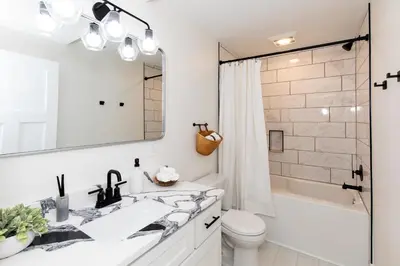 a white bathroom with a sink and a tub and a toilet at Family Duplex Suite in Downtown Sandusky Sleeps 12! in Sandusky