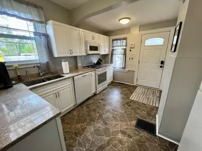 a kitchen with white cabinets and a tile floor at Cozy at Anderson Towne Center in Cincinnati