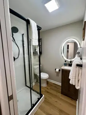 a bathroom with a shower and a toilet and a mirror at Just like home w Pool & Pool table in Milford