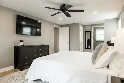 a bedroom with a white bed and a ceiling fan at Amazing Pool & Walk to the Park in Cincinnati
