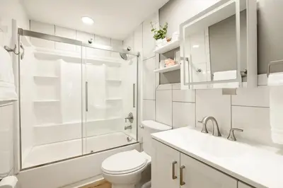 a white bathroom with a toilet and a shower at Amazing Pool & Walk to the Park in Cincinnati