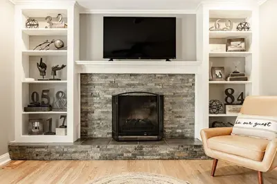 a living room with a fireplace with a flat screen tv at Amazing Pool & Walk to the Park in Cincinnati