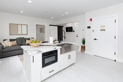 a kitchen and living room with white cabinets and a couch at Adjoining Condominium Units Sleeps 12 in Downtown Sandusky! in Sandusky