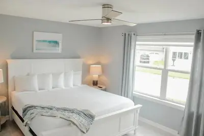 a white bedroom with a white bed and a window at At the Beach - Old Homestead Beach House in Huron