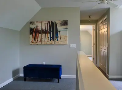 a room with a blue ottoman and surfboards on the wall at At the Beach - Old Homestead Beach House in Huron