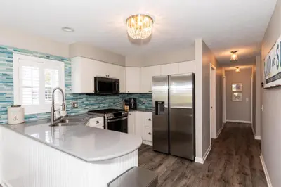 a kitchen with a stainless steel refrigerator and white cabinets at At the Beach - Old Homestead Beach House in Huron