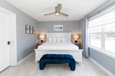 a bedroom with a white bed and a blue bench at At the Beach - Old Homestead Beach House in Huron