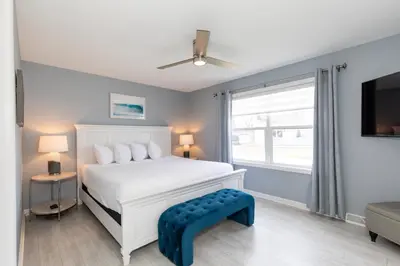 a bedroom with a white bed and a large window at At the Beach - Old Homestead Beach House in Huron