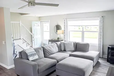 a living room with a couch and a staircase at At the Beach - Old Homestead Beach House in Huron