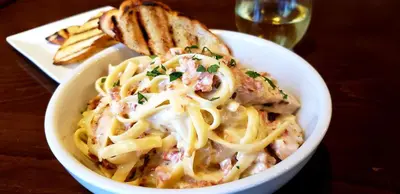 a bowl of pasta with bread and a glass of wine at Hyatt Place at The Hollywood Casino Pittsburgh South in Washington