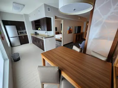 a kitchen and living room with a wooden table and chairs at Hyatt Place at The Hollywood Casino Pittsburgh South in Washington